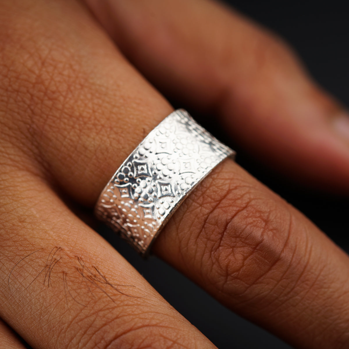 a close up of a person's hand wearing a silver ring