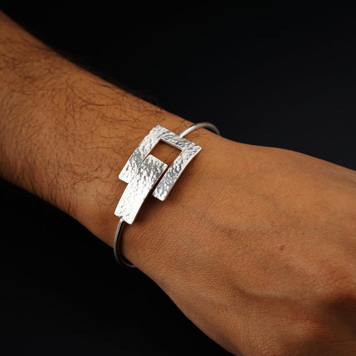 a person wearing a silver bracelet on their arm