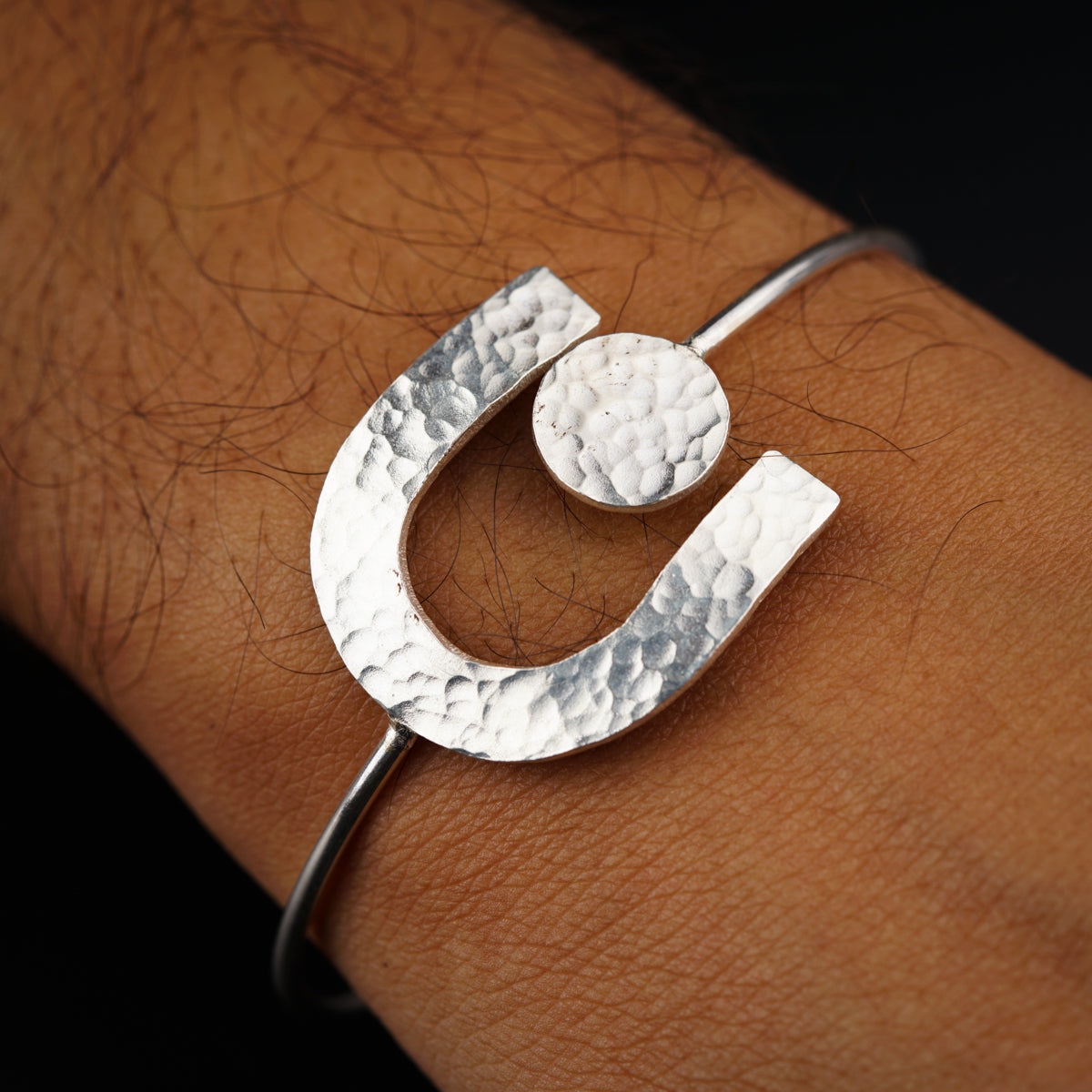 a close up of a person's arm wearing a silver bracelet