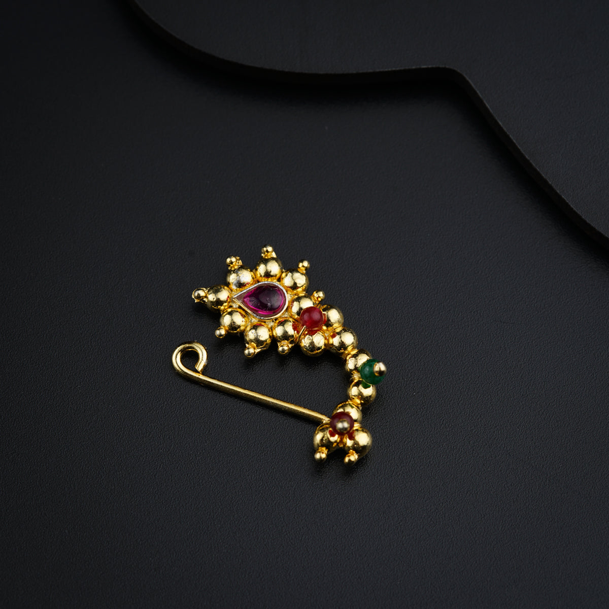 a gold brooch with a red and green stone
