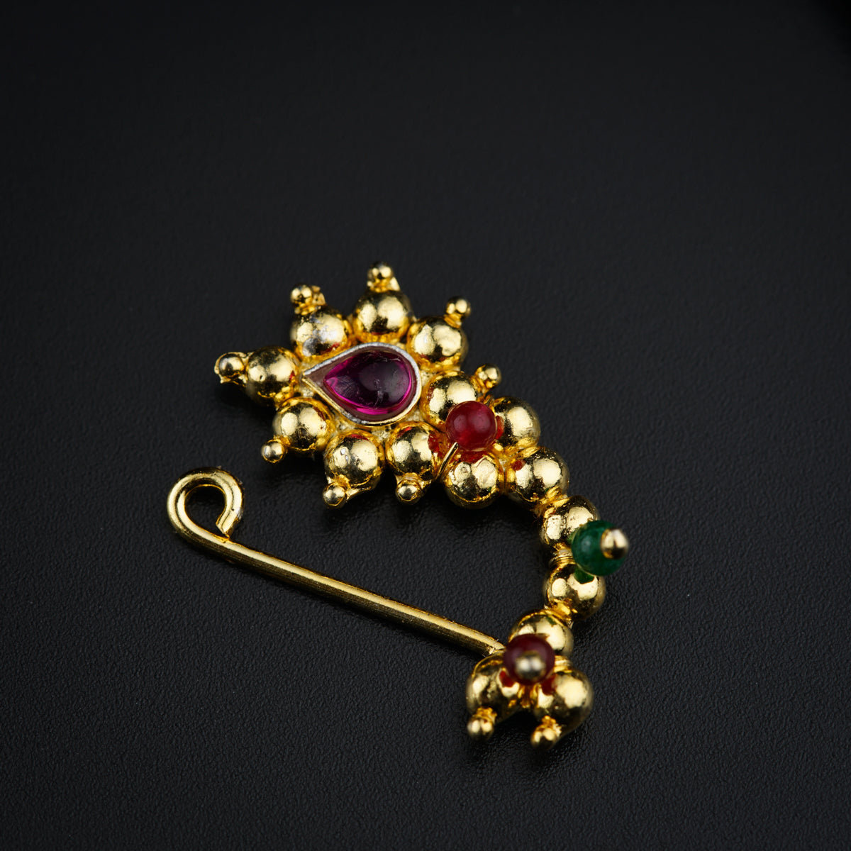 a gold brooch with a red, green and yellow stone