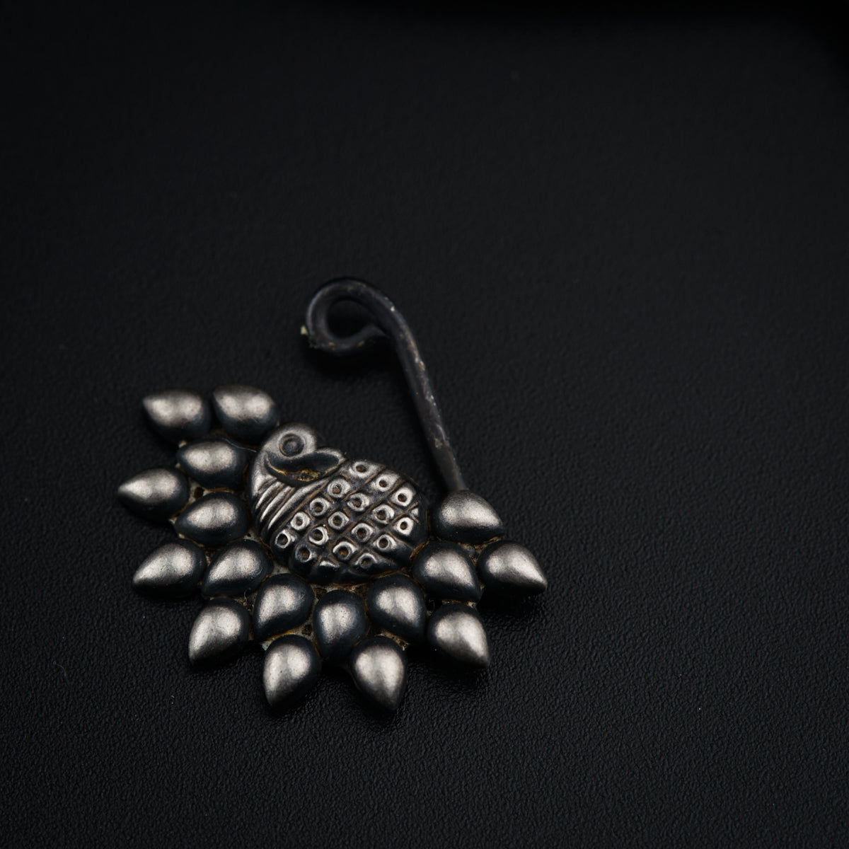 a brooch with a bird on it on a black surface