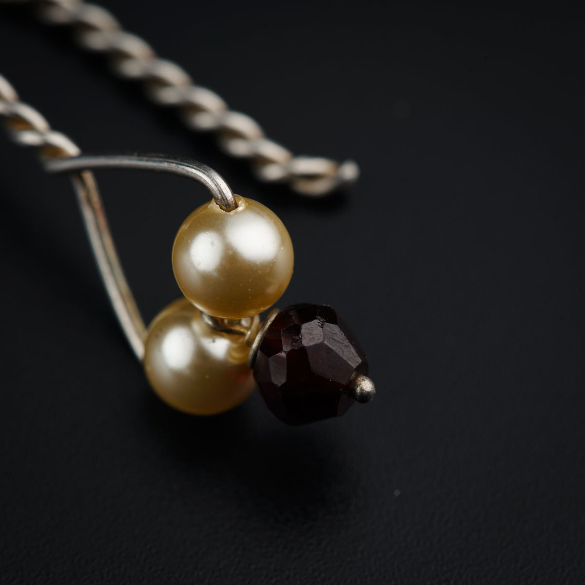 a pair of pearls and a chain on a black surface