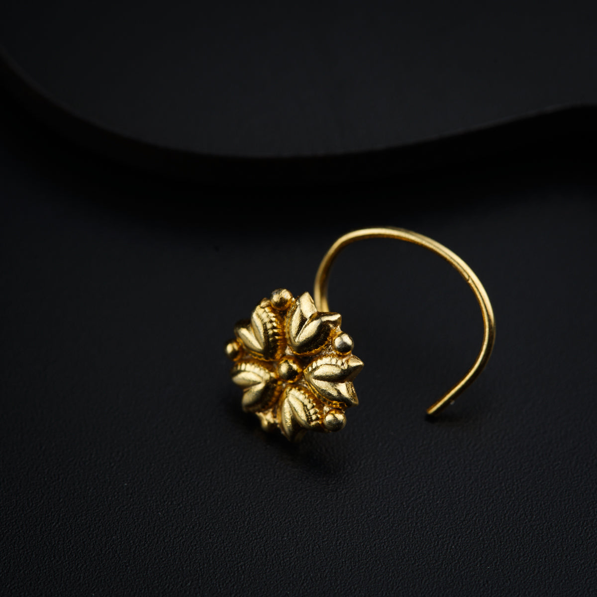 a pair of gold earrings on a black surface