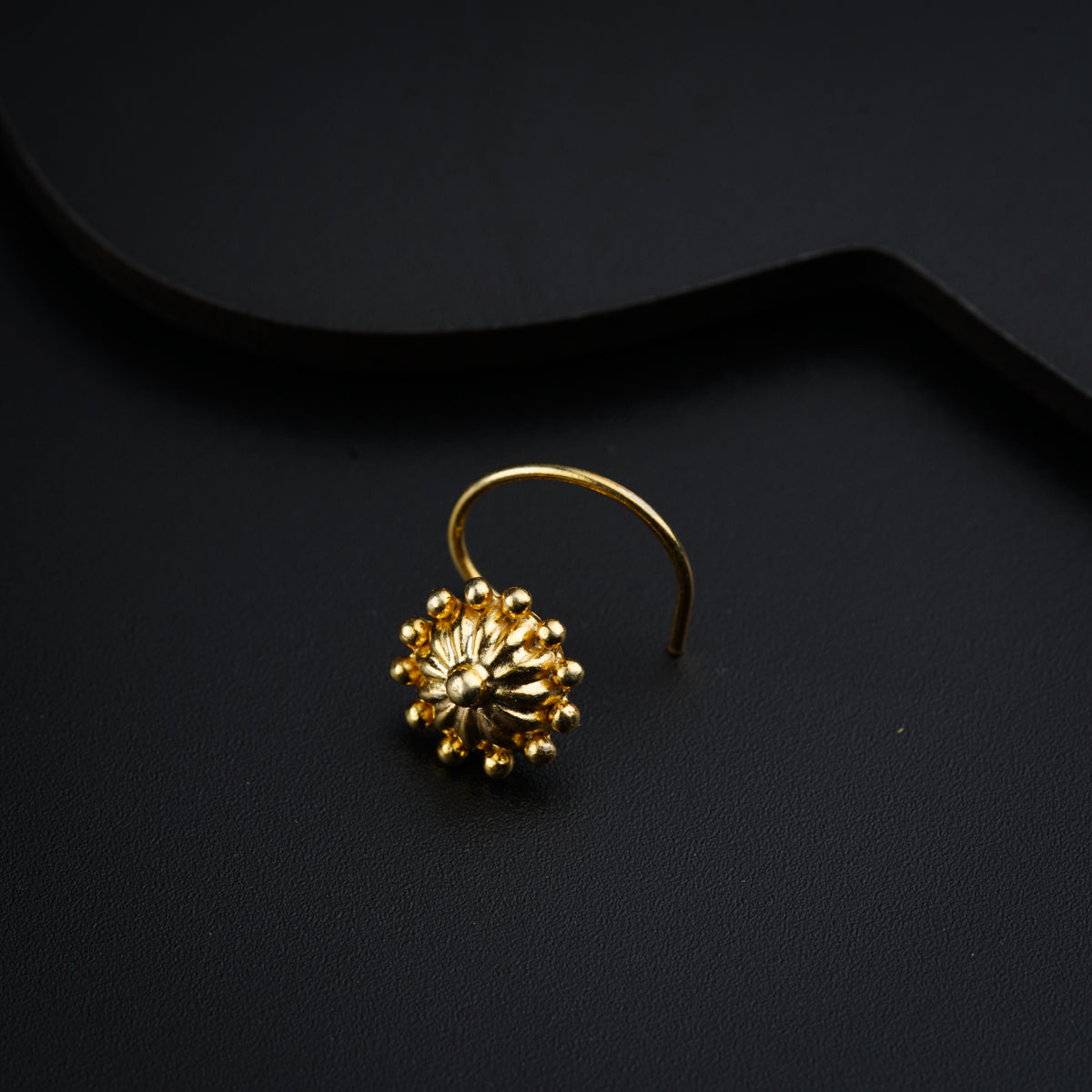 a pair of gold earrings on a black surface