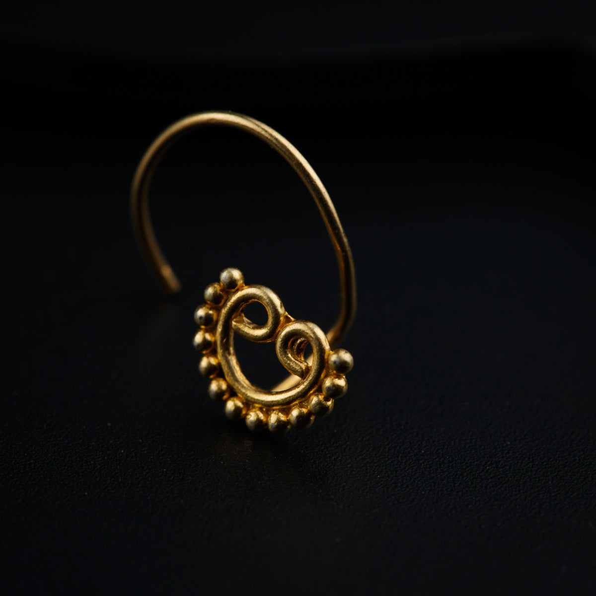 a gold nose ring on a black surface