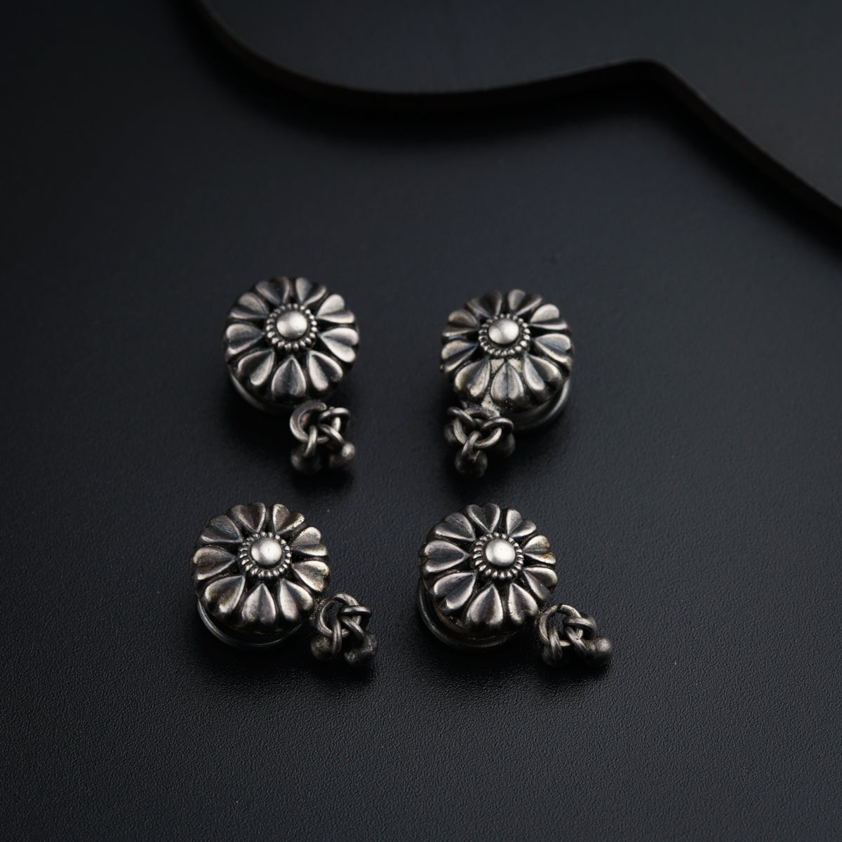 a pair of silver earrings sitting on top of a table