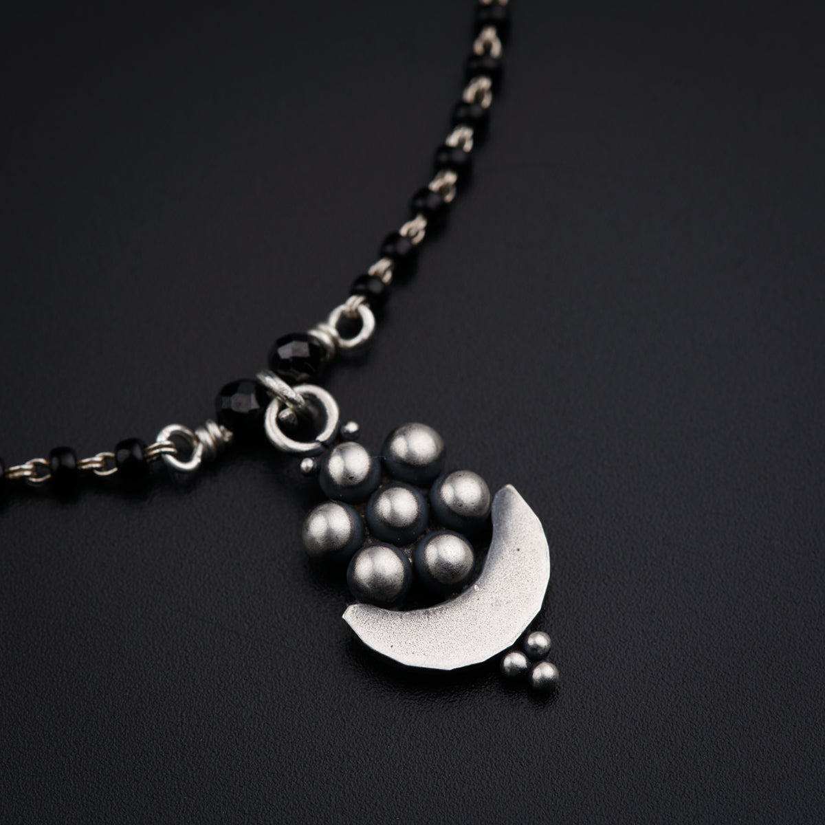 a necklace with a crescent and pearls hanging from it