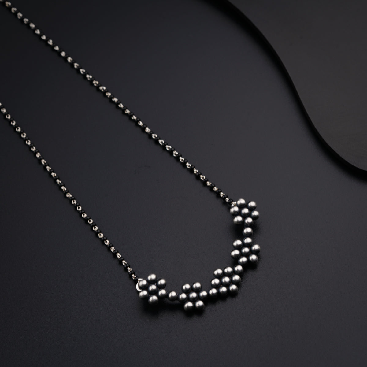 a necklace with balls on a black surface