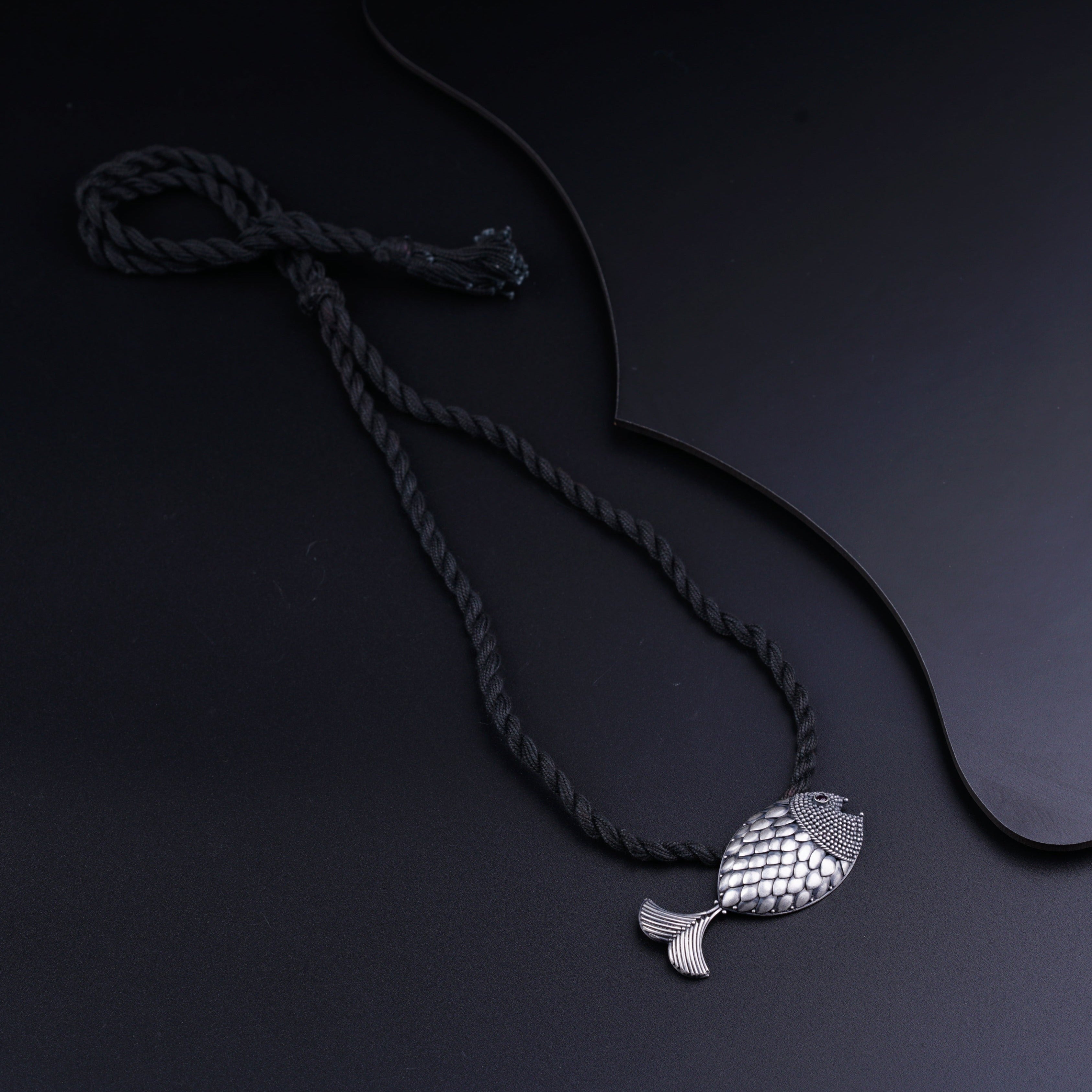 a necklace with a fish on a black background