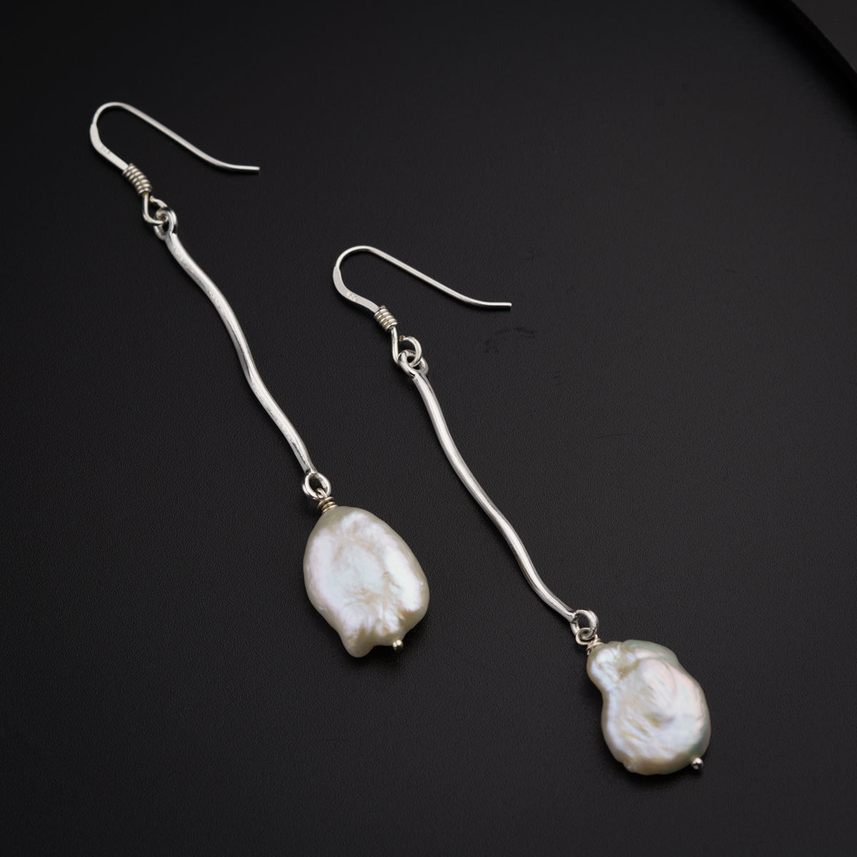a pair of silver earrings with a white pearl