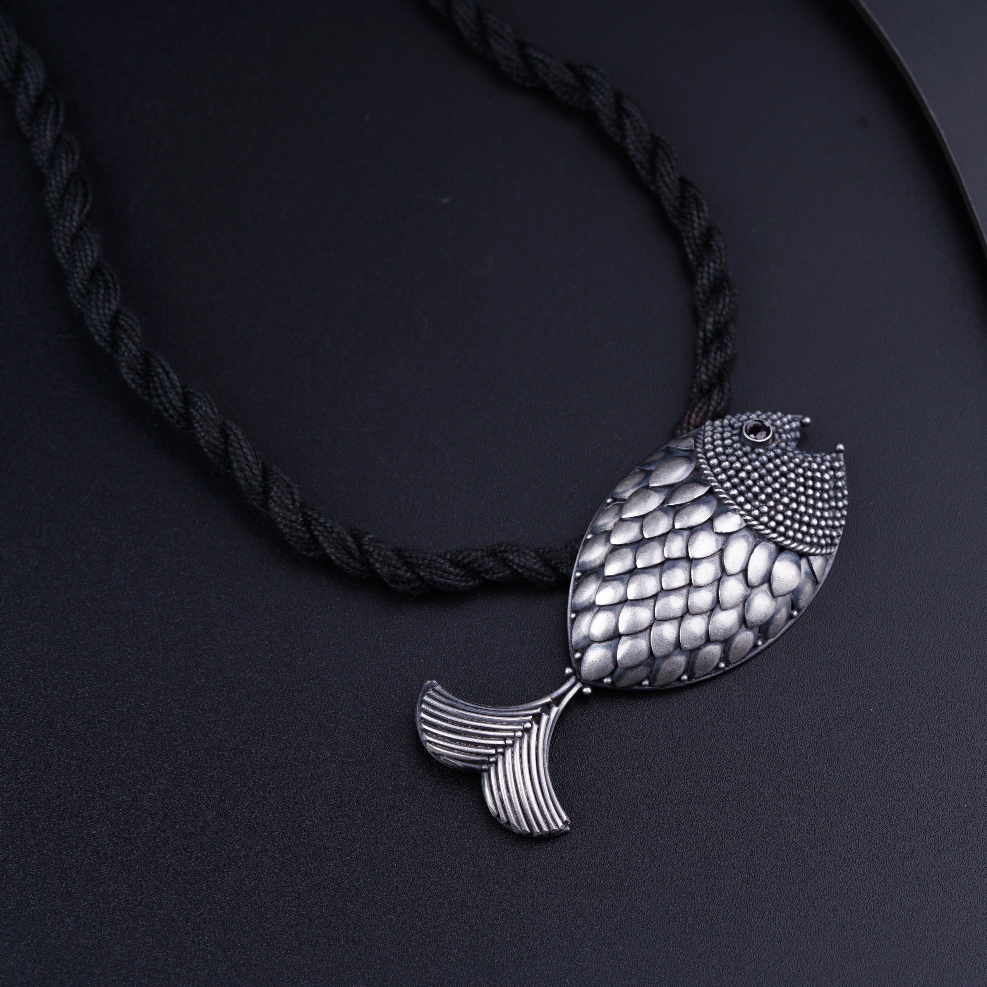 a silver fish pendant on a black cord