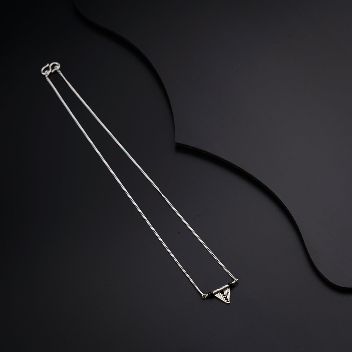 a pair of silver necklaces on a black surface