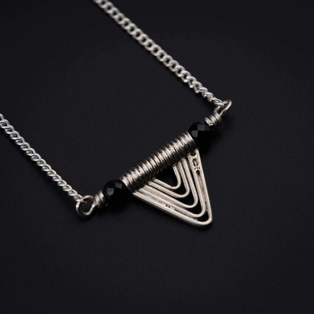 a necklace with a triangle shaped pendant on a chain