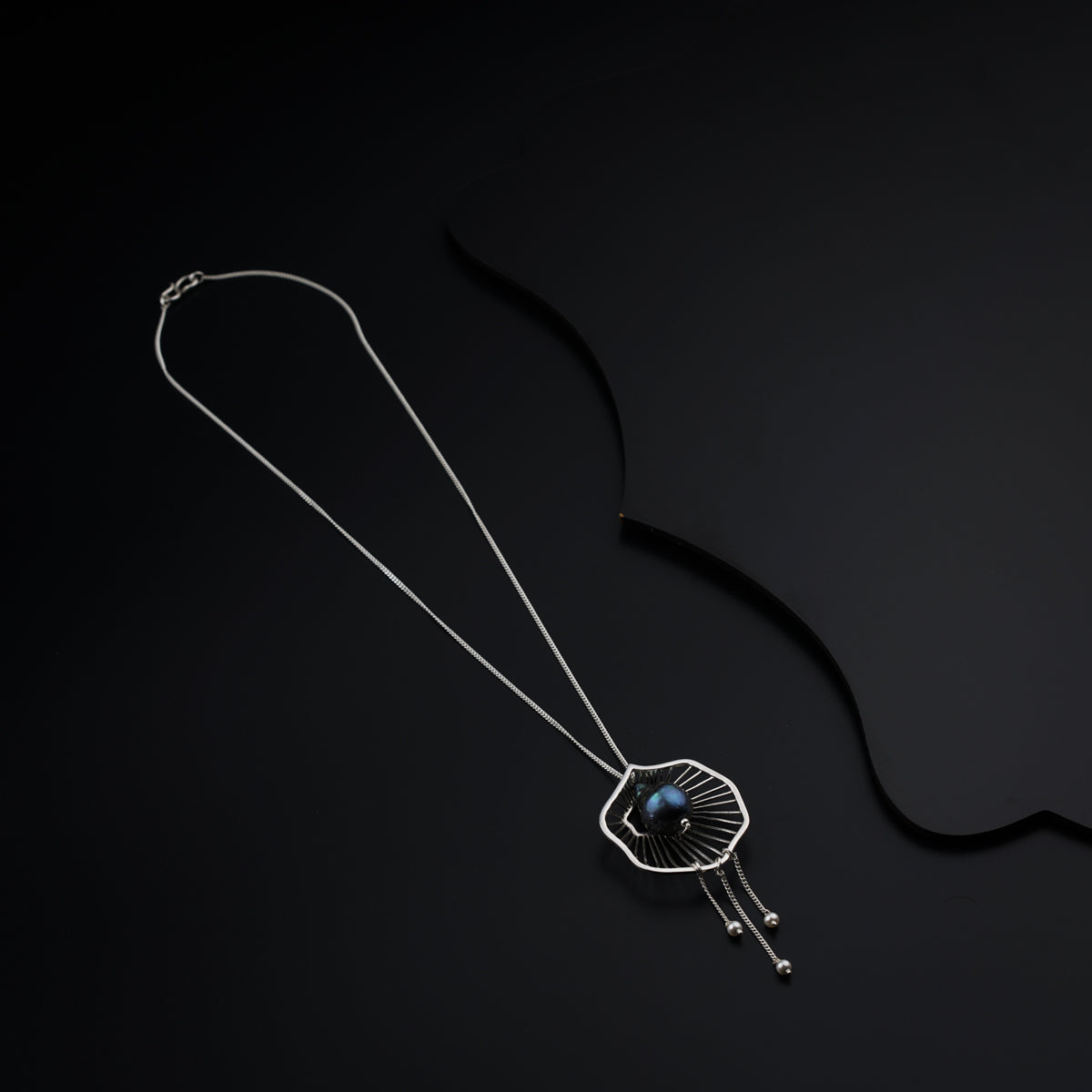 a black background with a silver necklace and a pendant