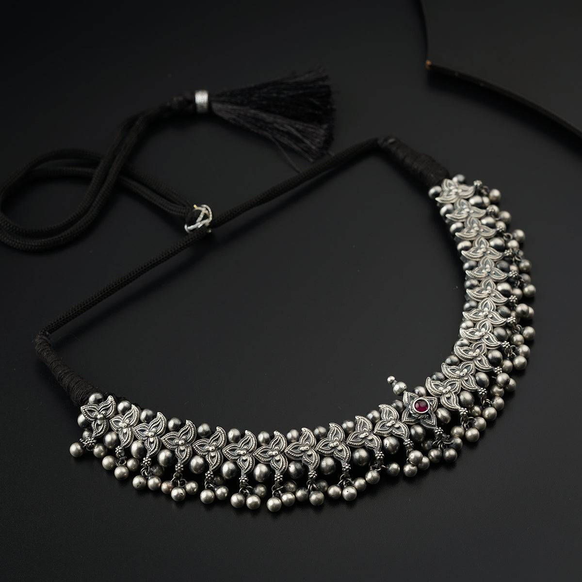 a necklace with beads and tassels on a black surface