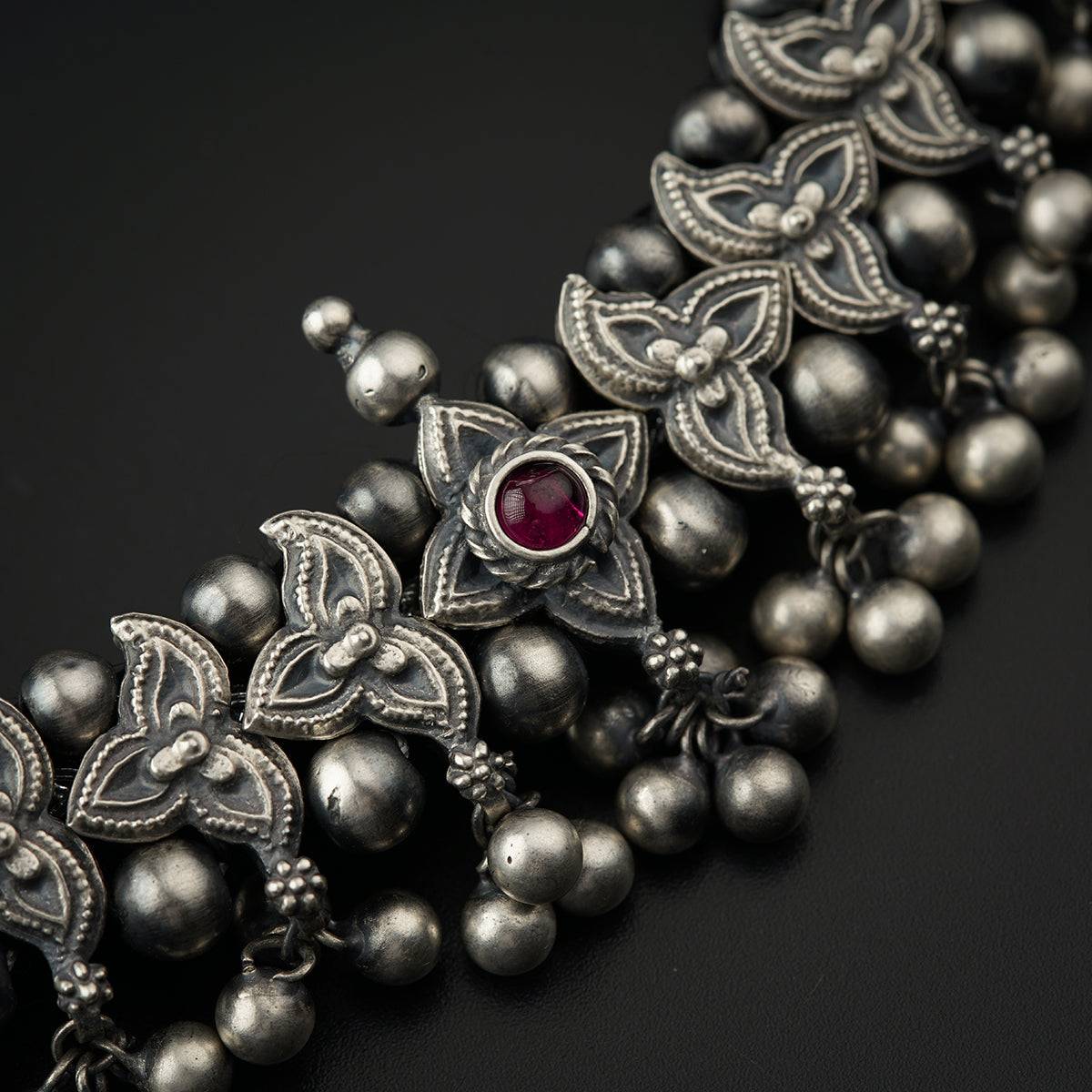 a close up of a necklace with a red stone