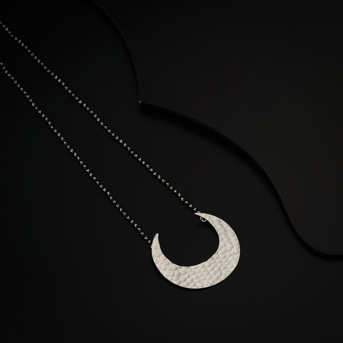 a necklace with a crescent on a black background