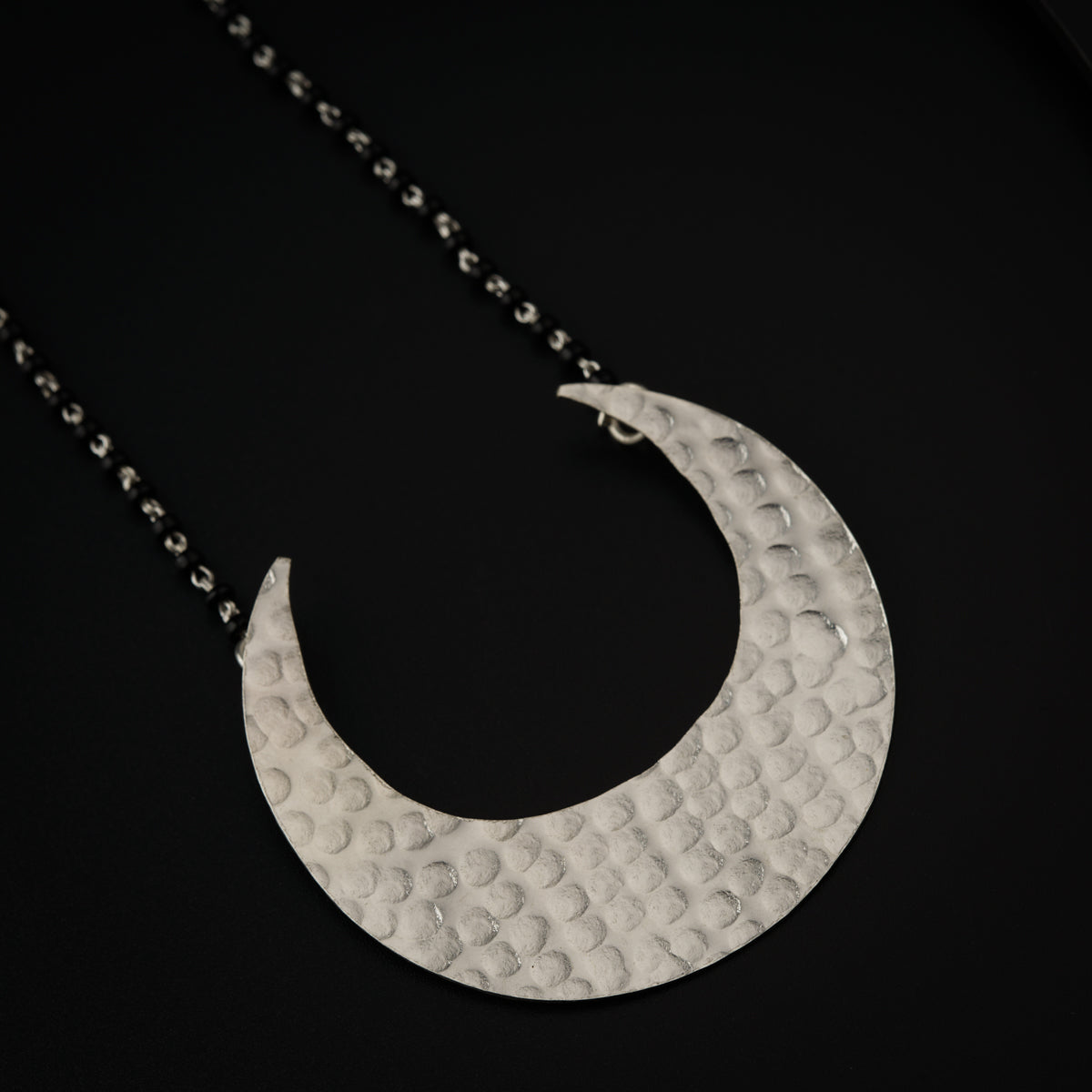 a silver crescent necklace on a black background