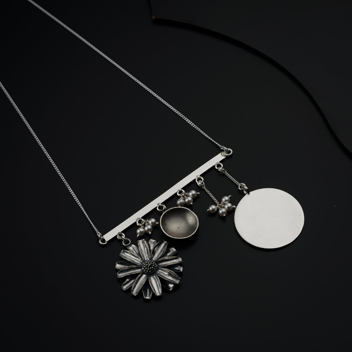 a necklace with a flower and a disc hanging from it