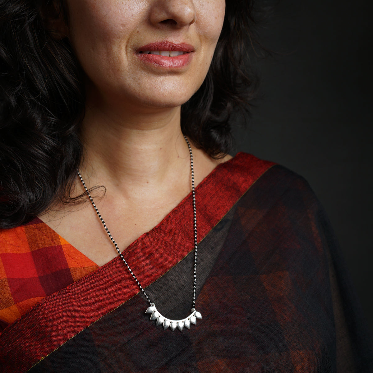 a woman wearing a red and black shirt and a necklace