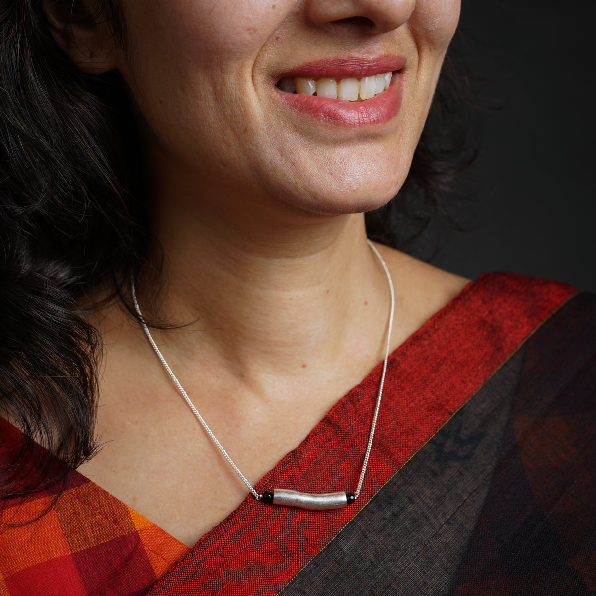 a woman wearing a necklace with a silver bar on it