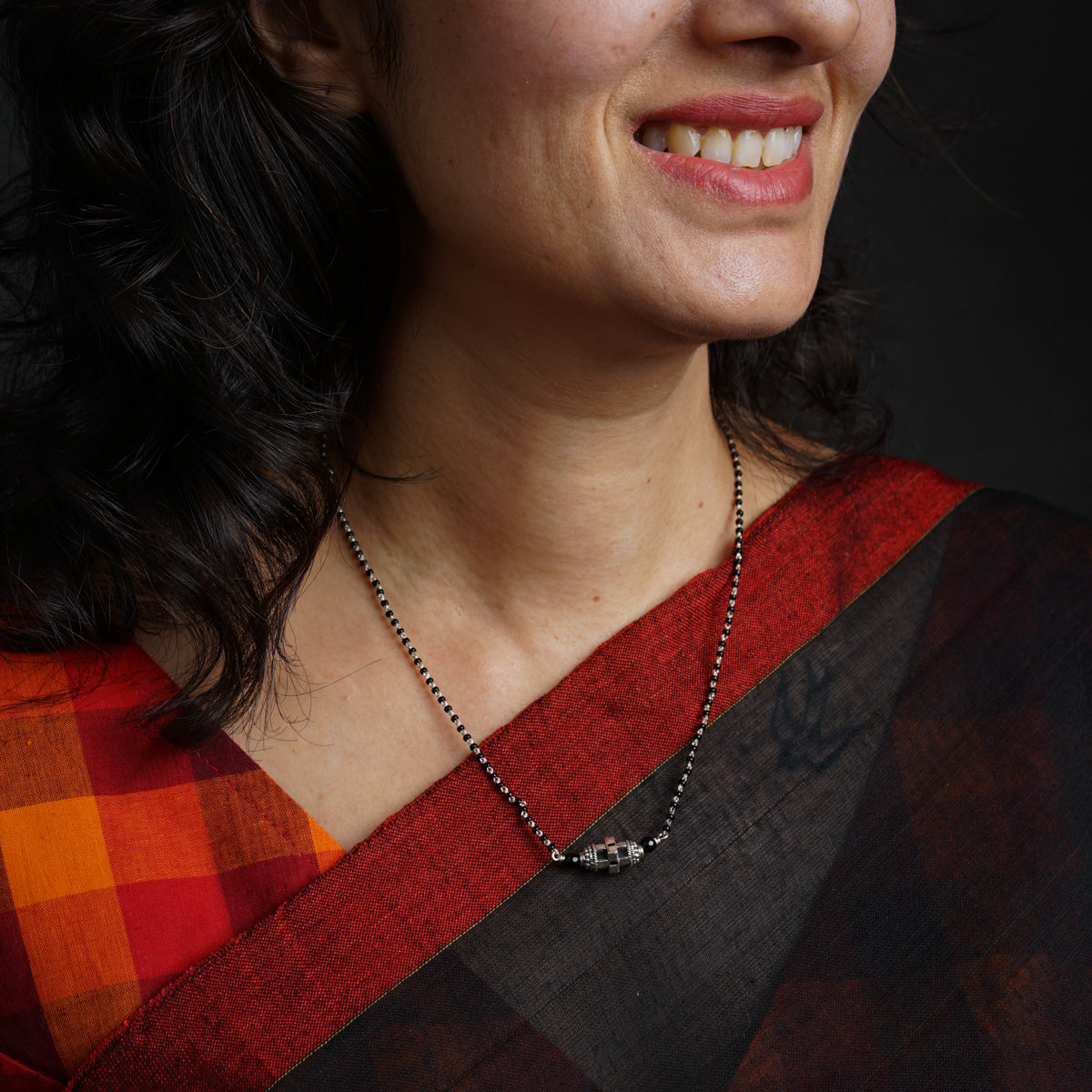 a woman wearing a red and black shirt and a necklace