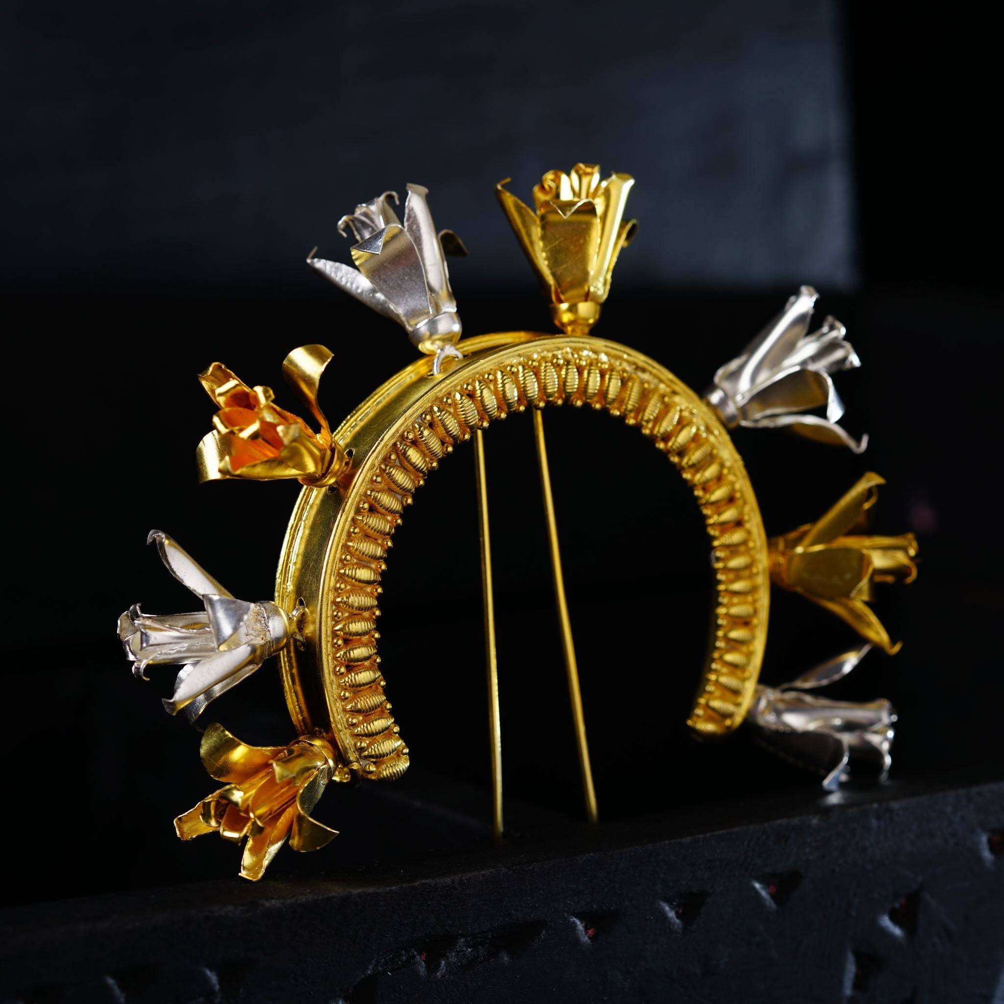 a close up of a gold brooch on a black surface