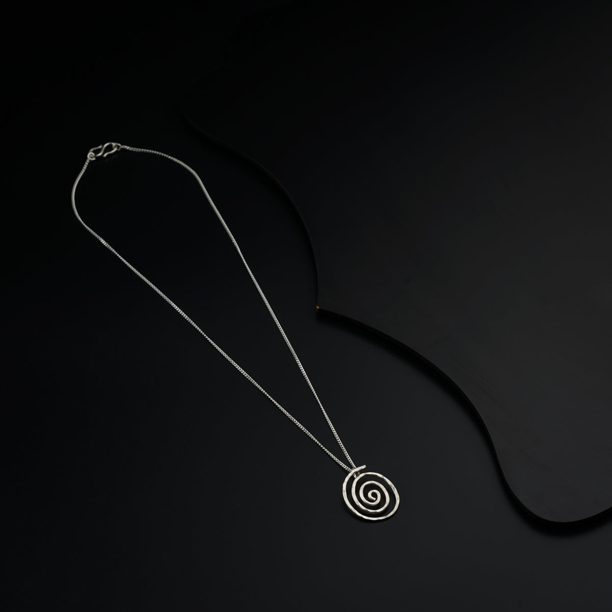 a necklace with a spiral design on a black background