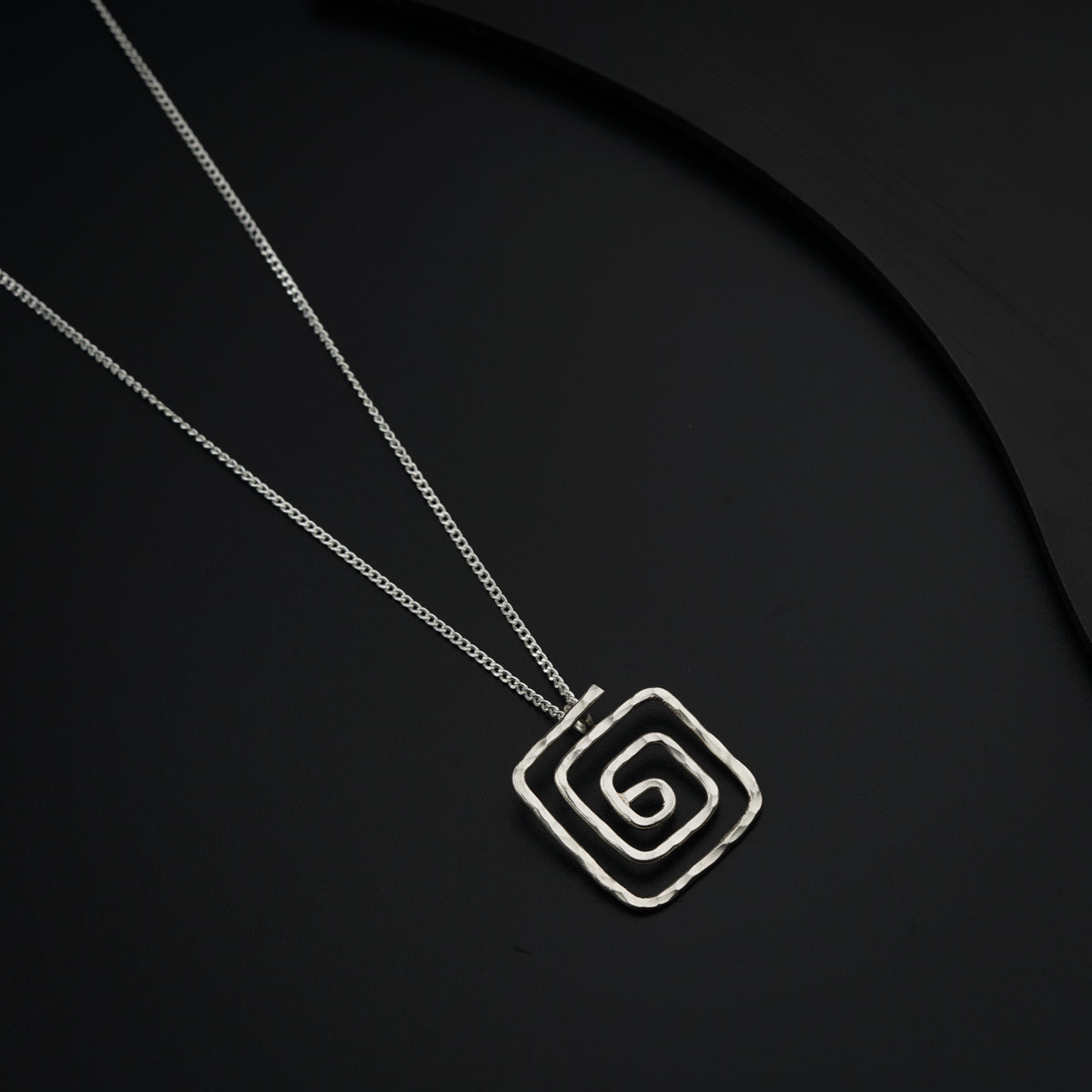 a necklace with a square pendant on a black background