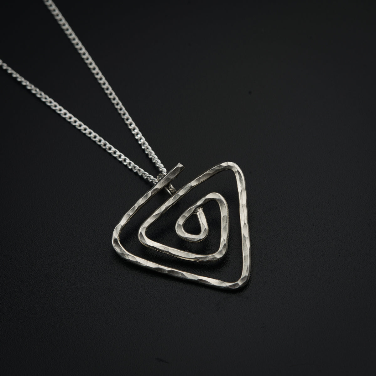a silver necklace with a triangle shaped pendant