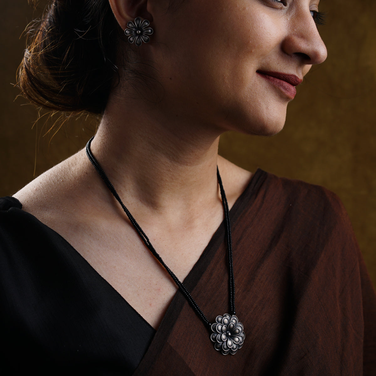 a woman wearing a necklace with a flower on it