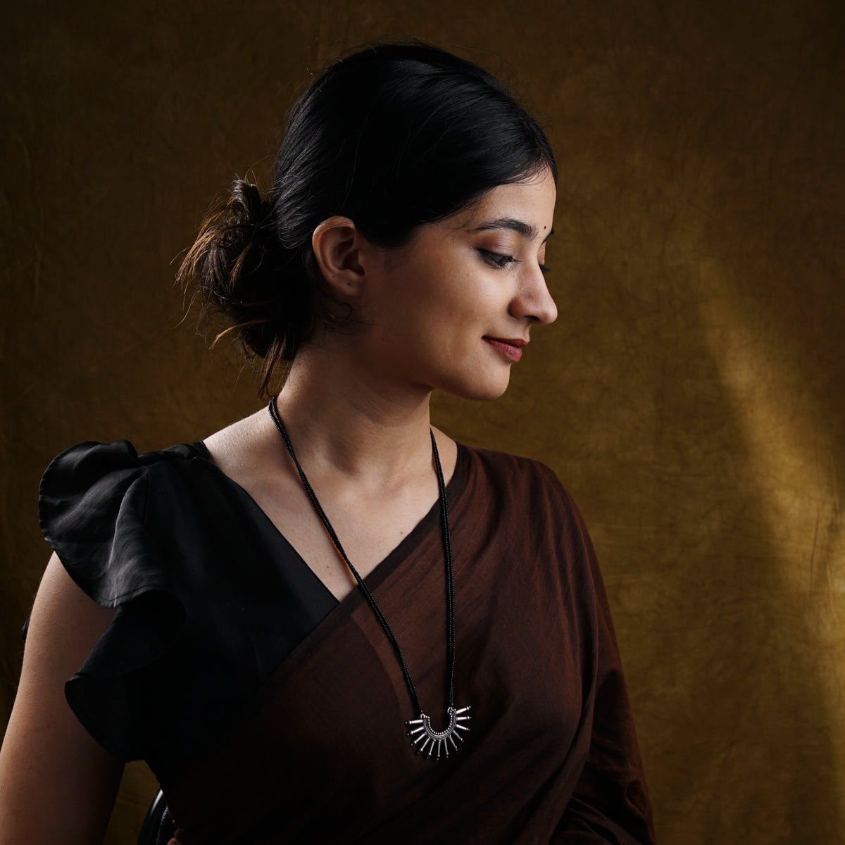 a woman in a brown shirt is holding a cell phone