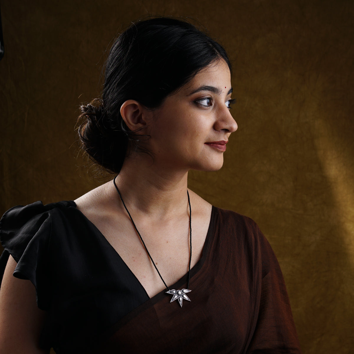 a woman wearing a brown dress and a necklace