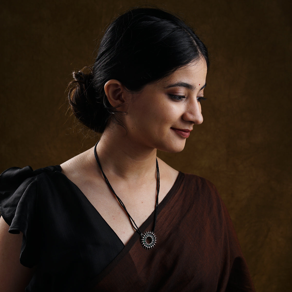 a woman wearing a brown dress and a necklace