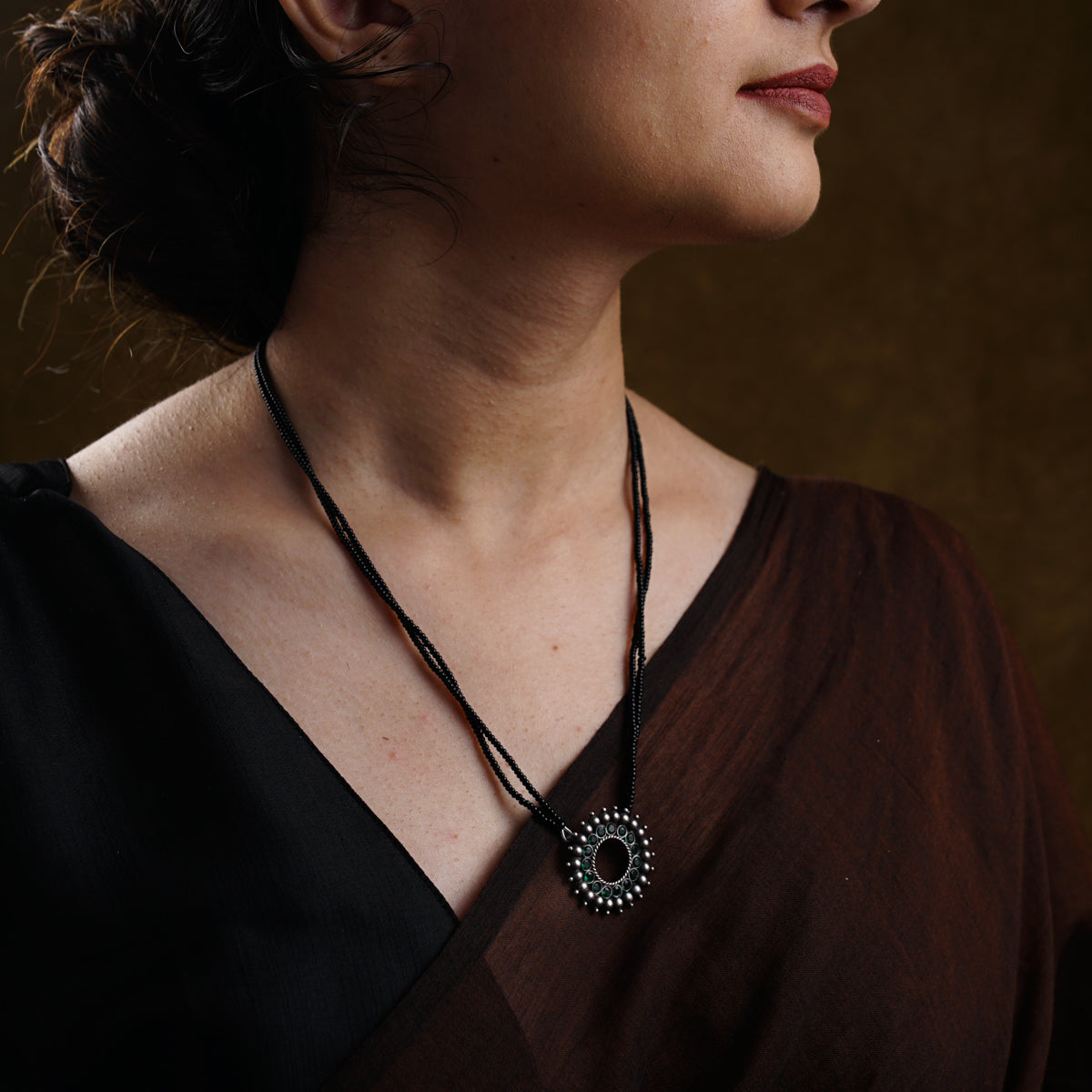a woman wearing a brown shirt and a necklace