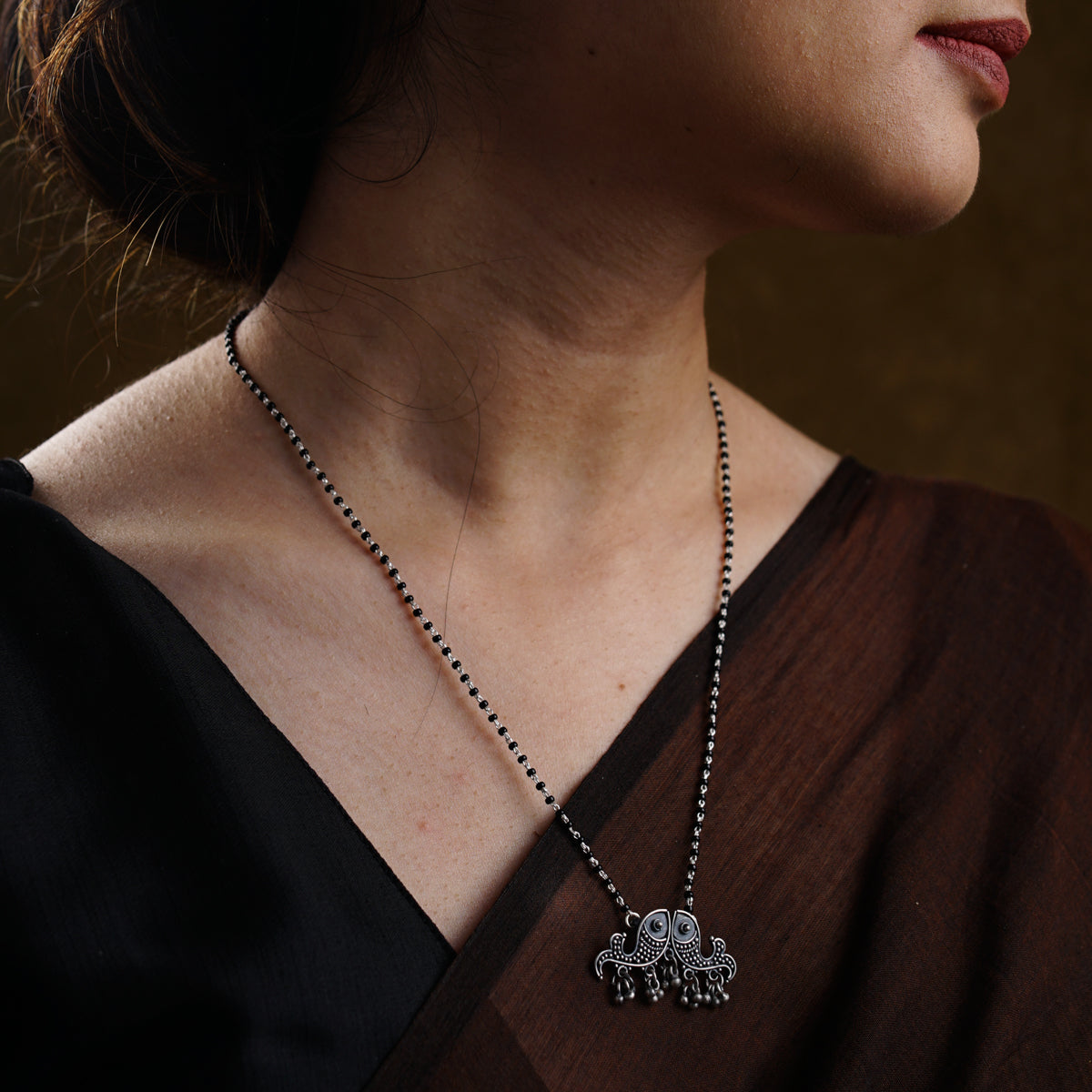 a woman wearing a necklace with two elephants on it