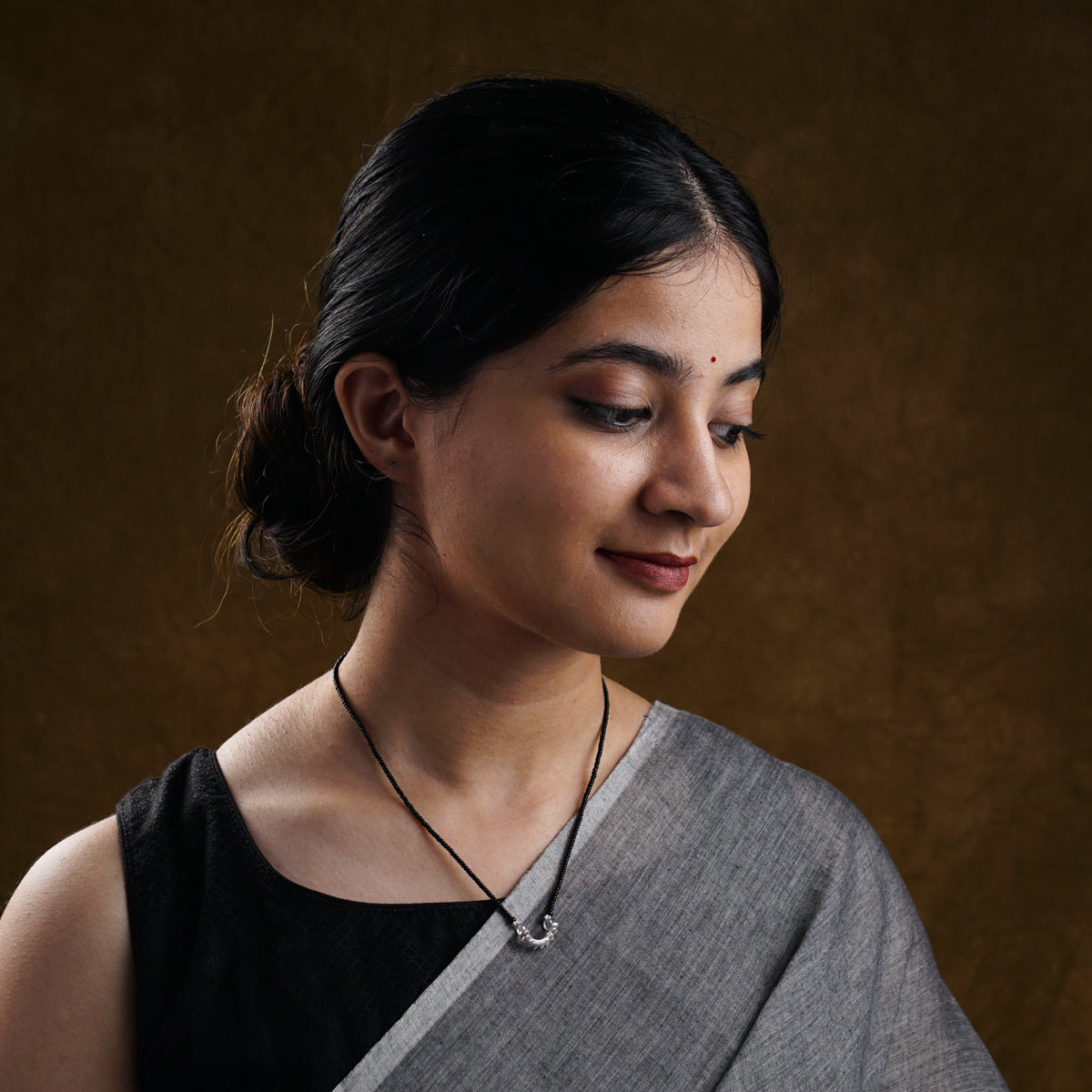 a woman wearing a necklace and a black top
