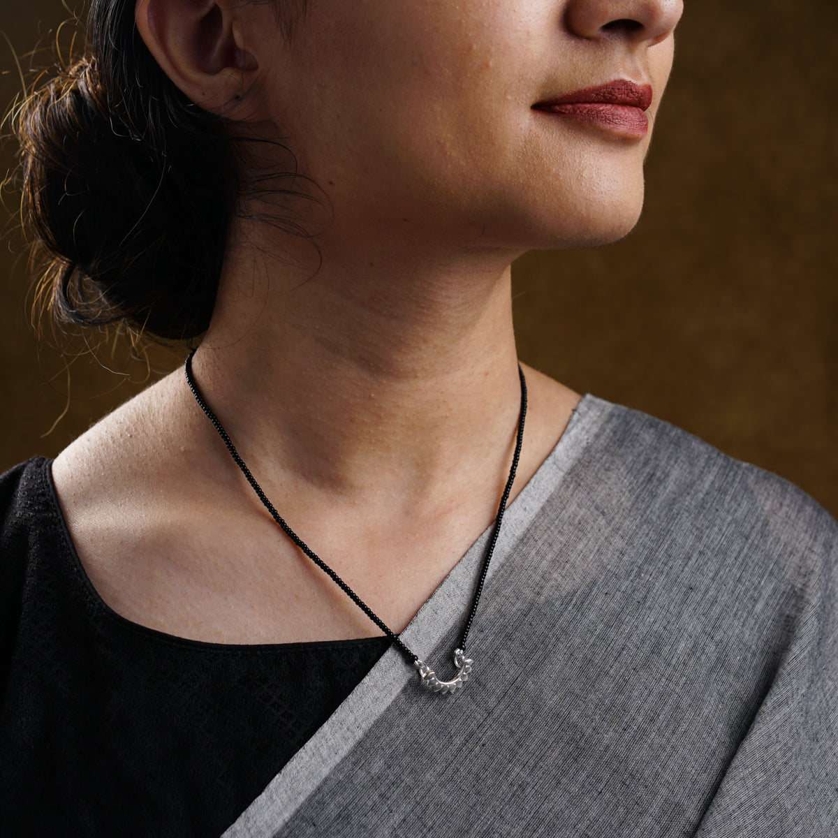 a woman wearing a necklace with a cross on it