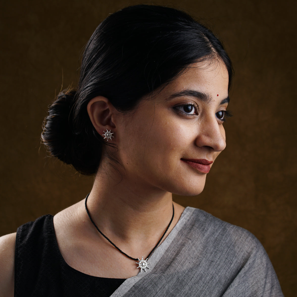 a woman wearing a necklace and a black top