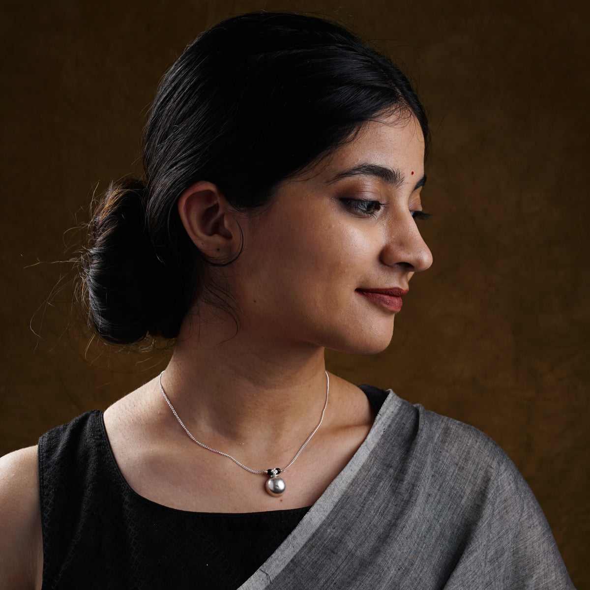 a woman wearing a black top and a silver necklace