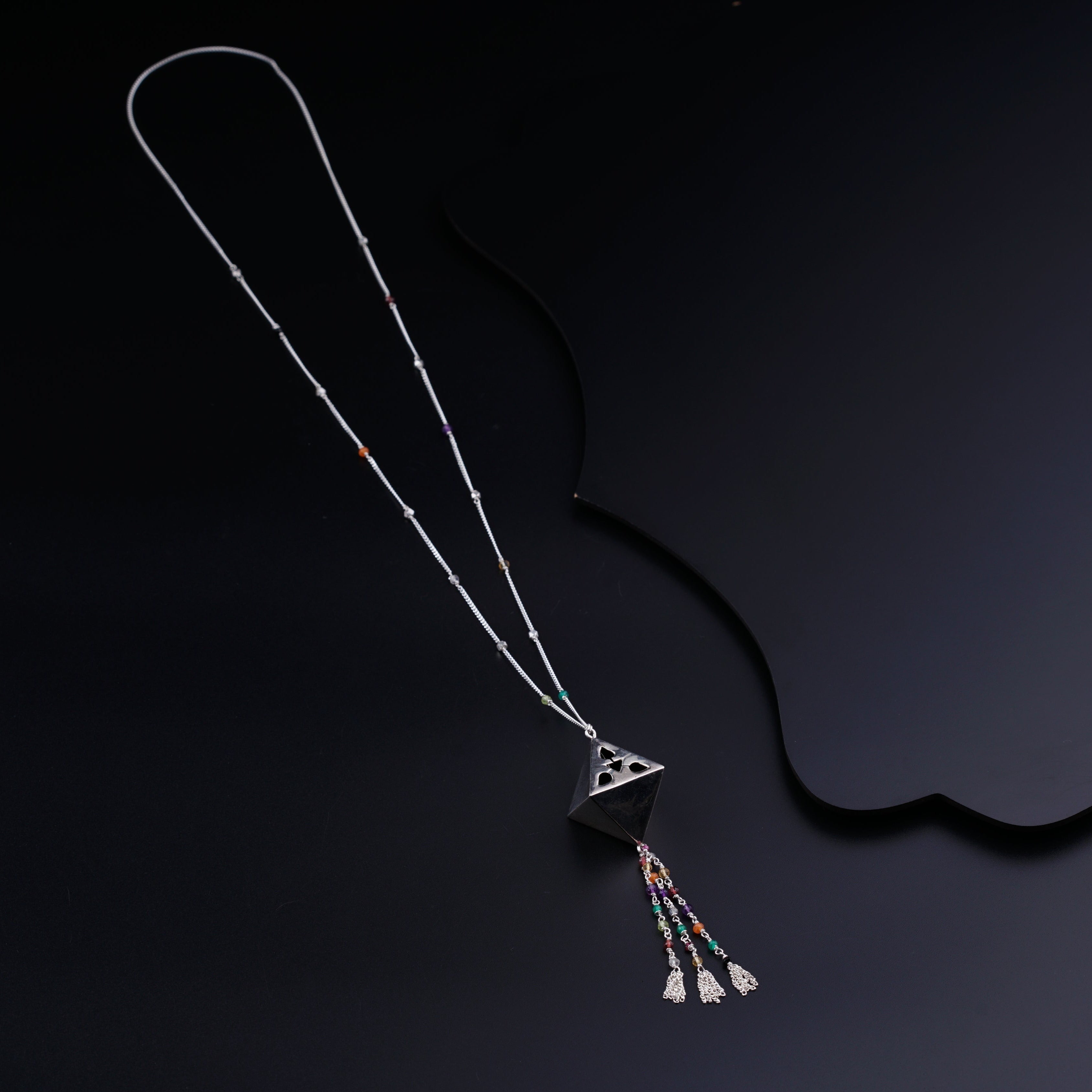 a necklace with a triangle and tassels hanging from it