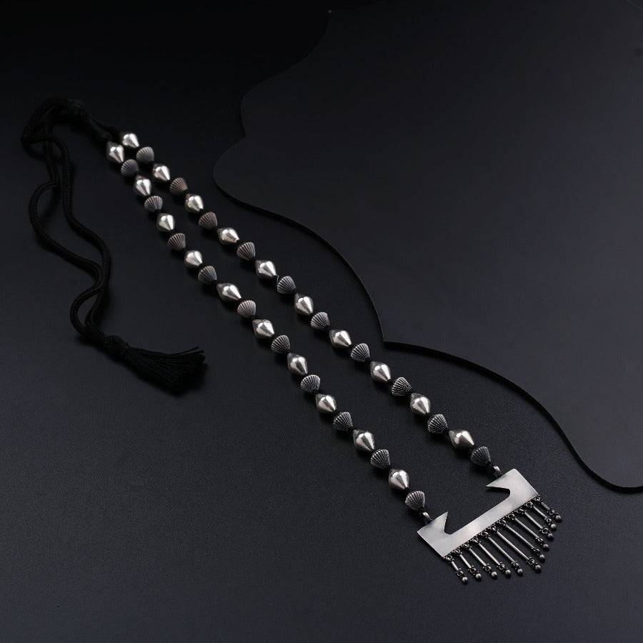 a black and silver necklace with beads and a tassel