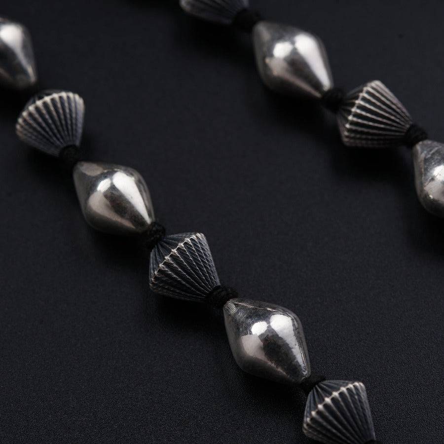 a close up of a necklace made of silver beads
