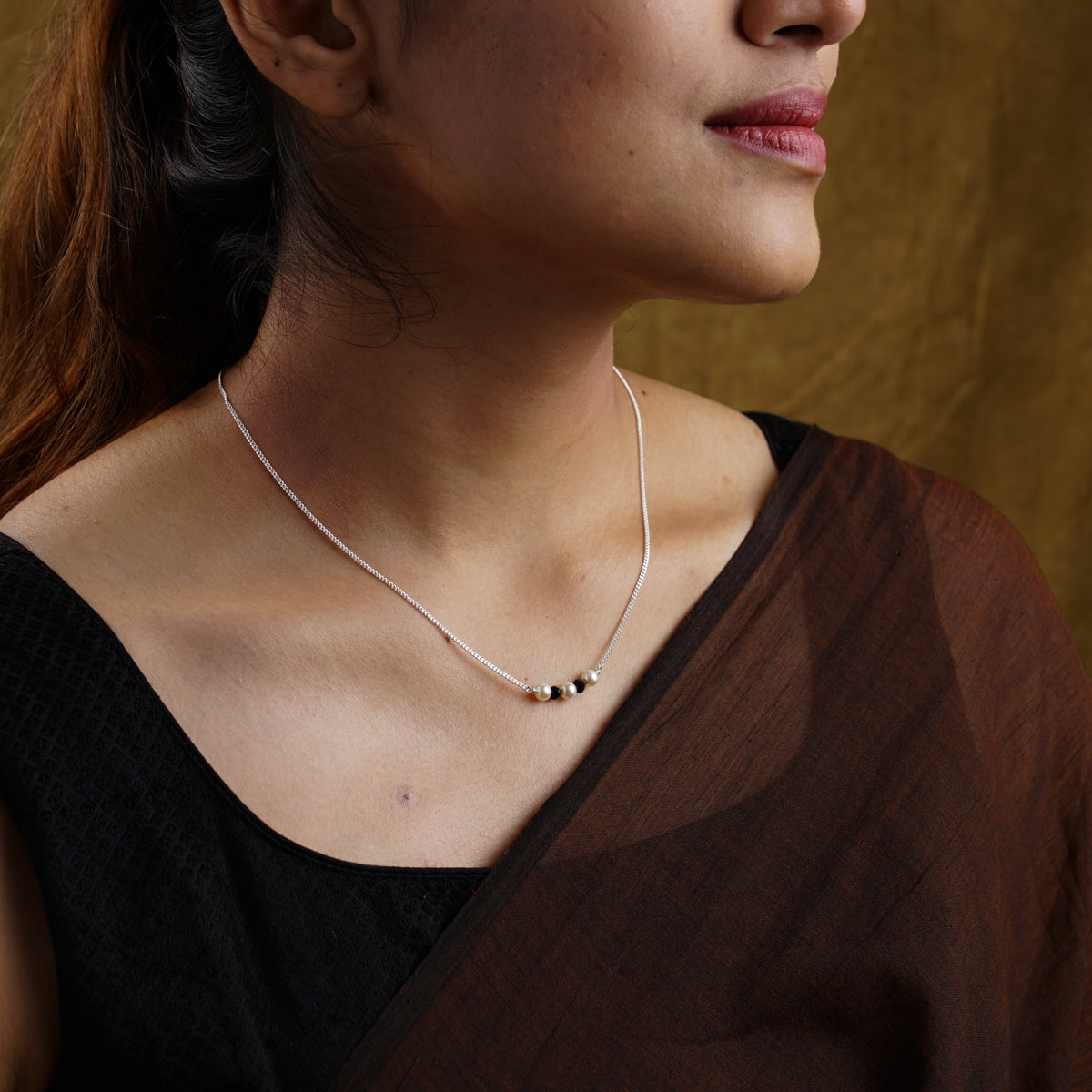 a woman wearing a black top and a white necklace