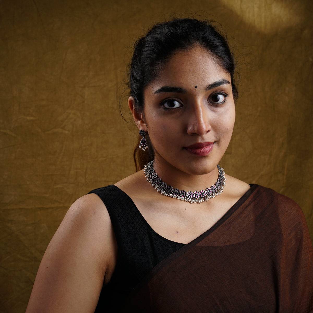 a woman in a brown dress with a necklace on her neck