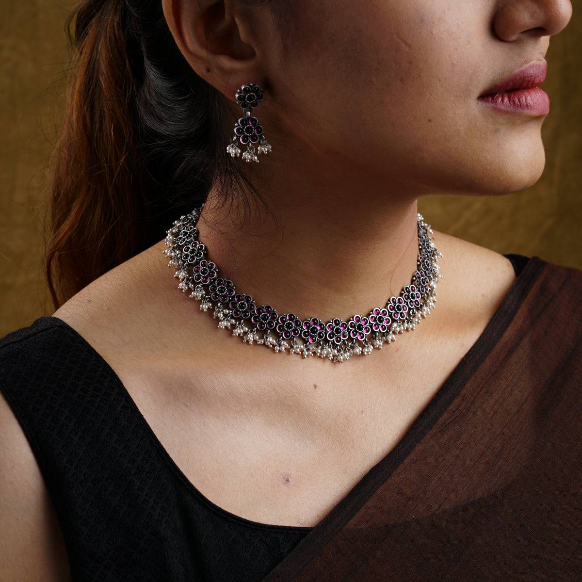 a close up of a woman wearing a necklace and earrings