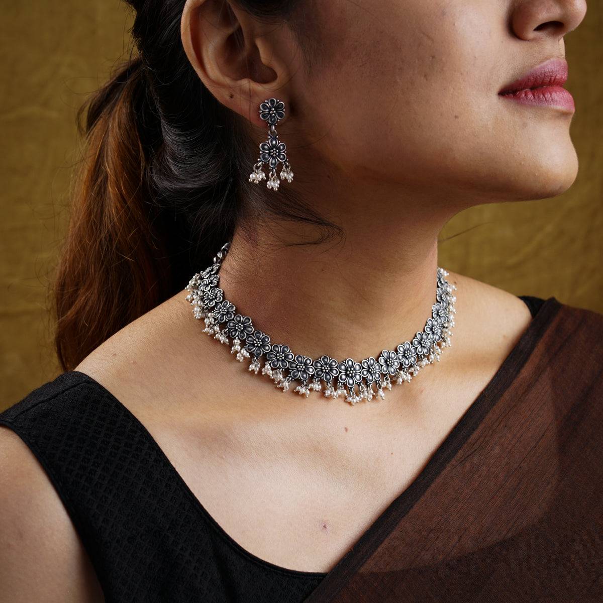 a close up of a woman wearing a necklace and earrings