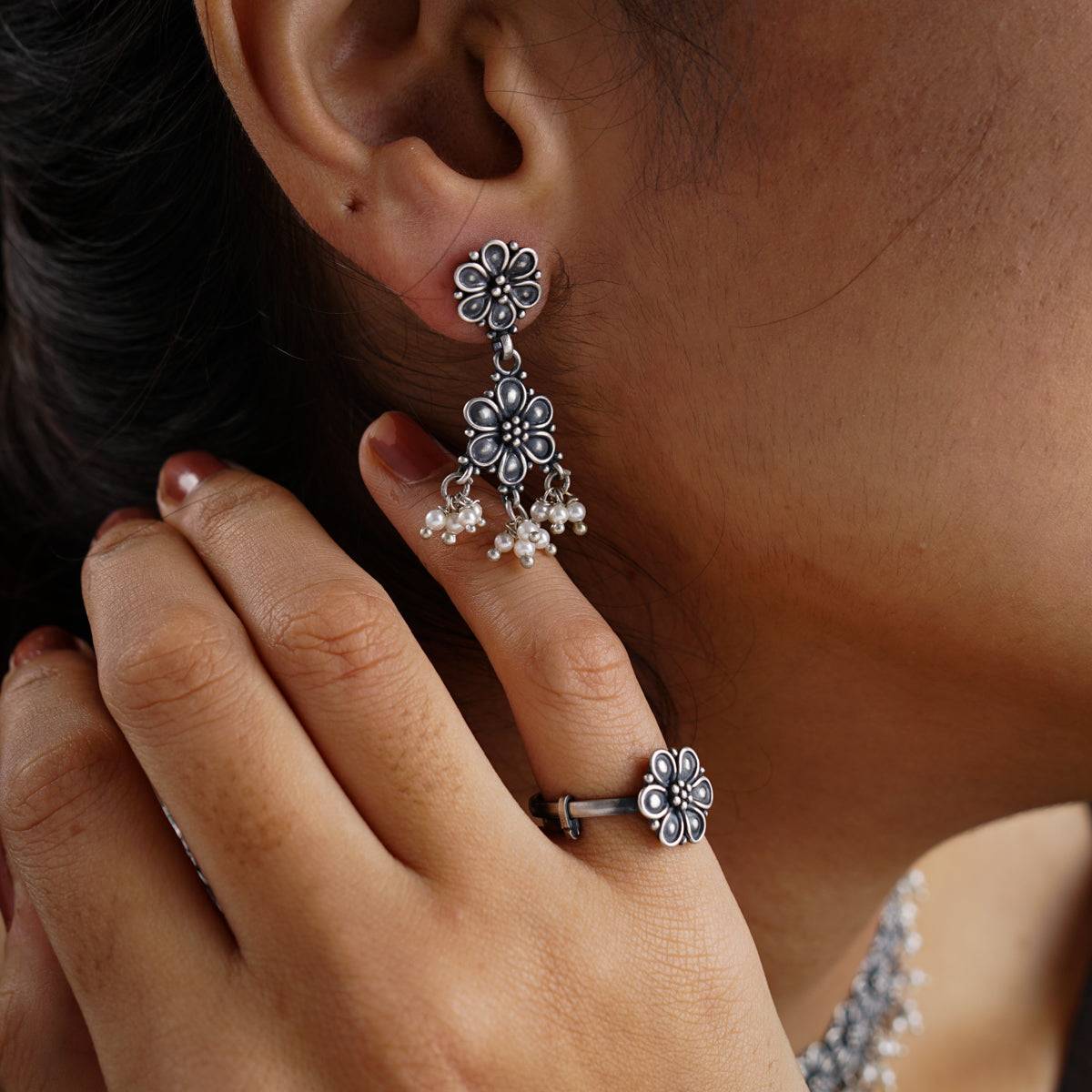 a close up of a person wearing a ring and earrings