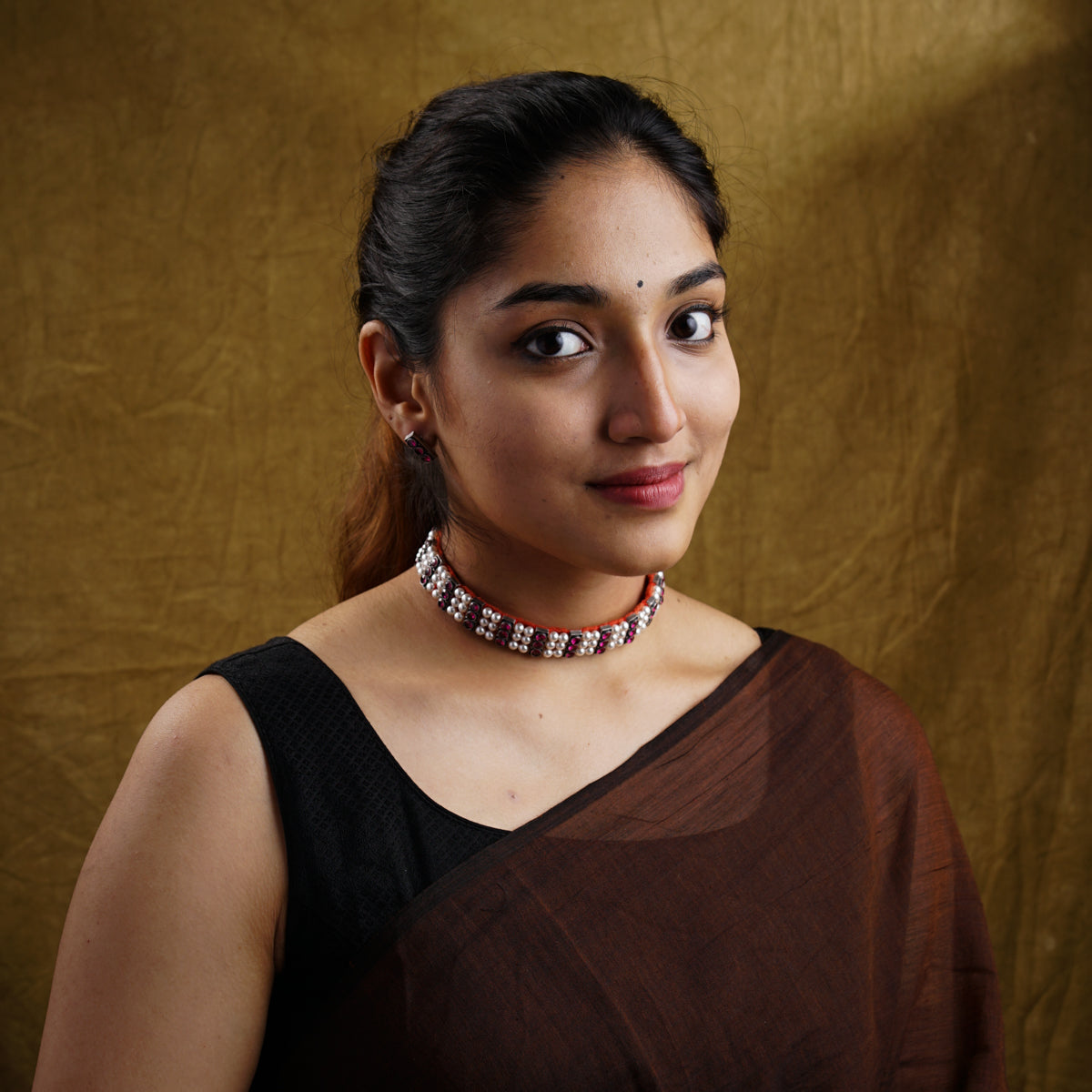 a woman wearing a brown dress and a necklace